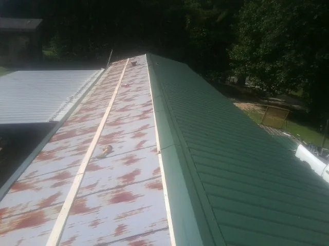 Old rusted panels beside newly installed green metal roofing — Wind Damage Roof Repair by Roofing Brothers in Valley View