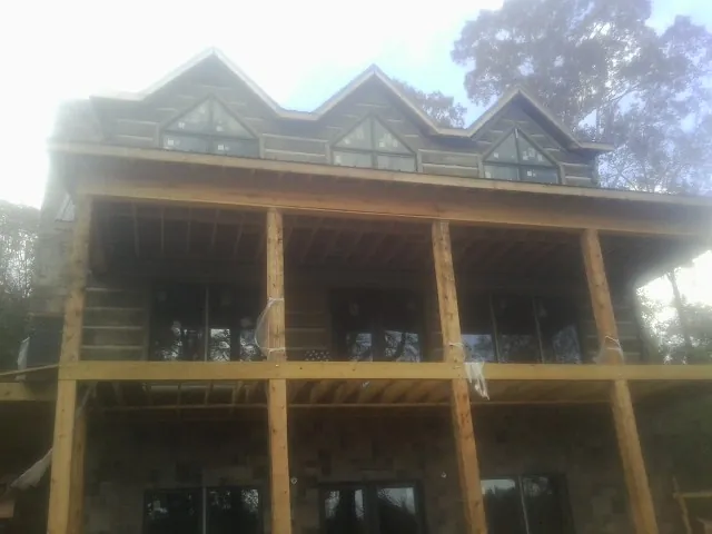 Dormers and porch framing on a large log home under construction — Roof Coating work by our crew in Valley View