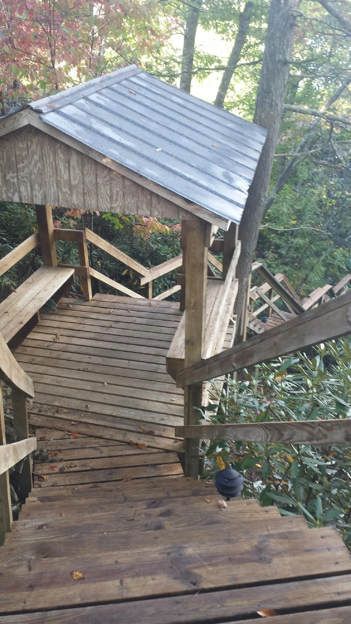 Metal roofed shelter over wooden steps on a wooded walkway — Skylight Repair & Installation work by our crew in Valley View